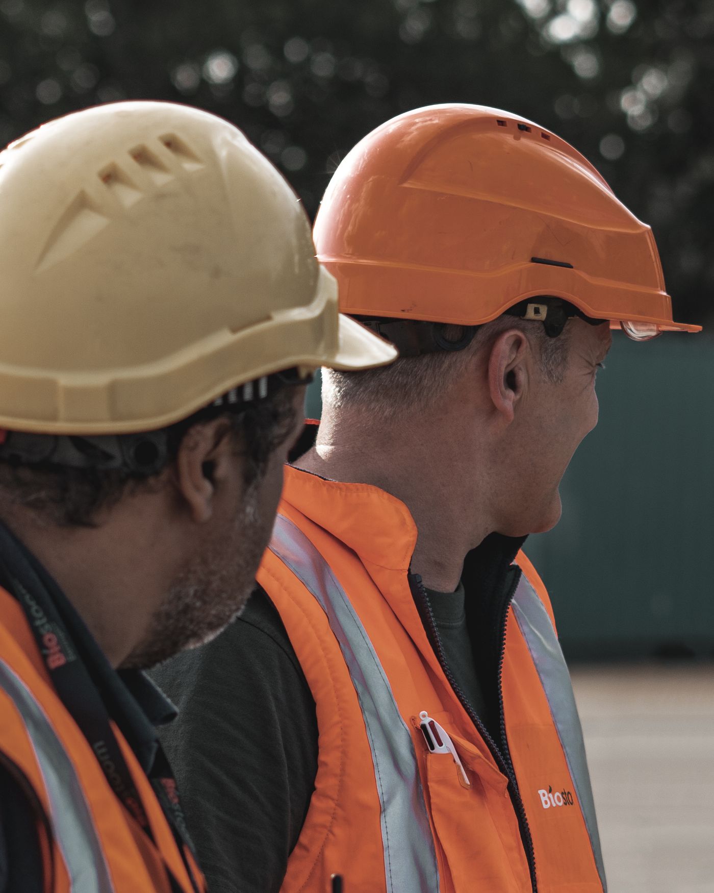 Two construction workers wearing safety helmets and high-visibility vests
